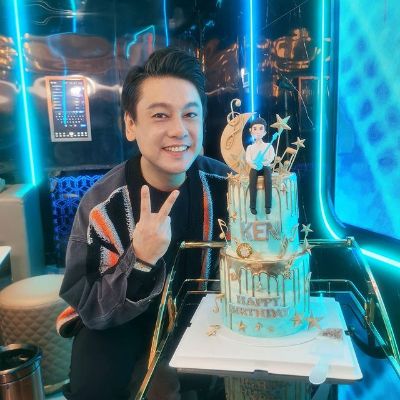 The two-storey cake has Ken Chu with a guitar sitting on top of it.